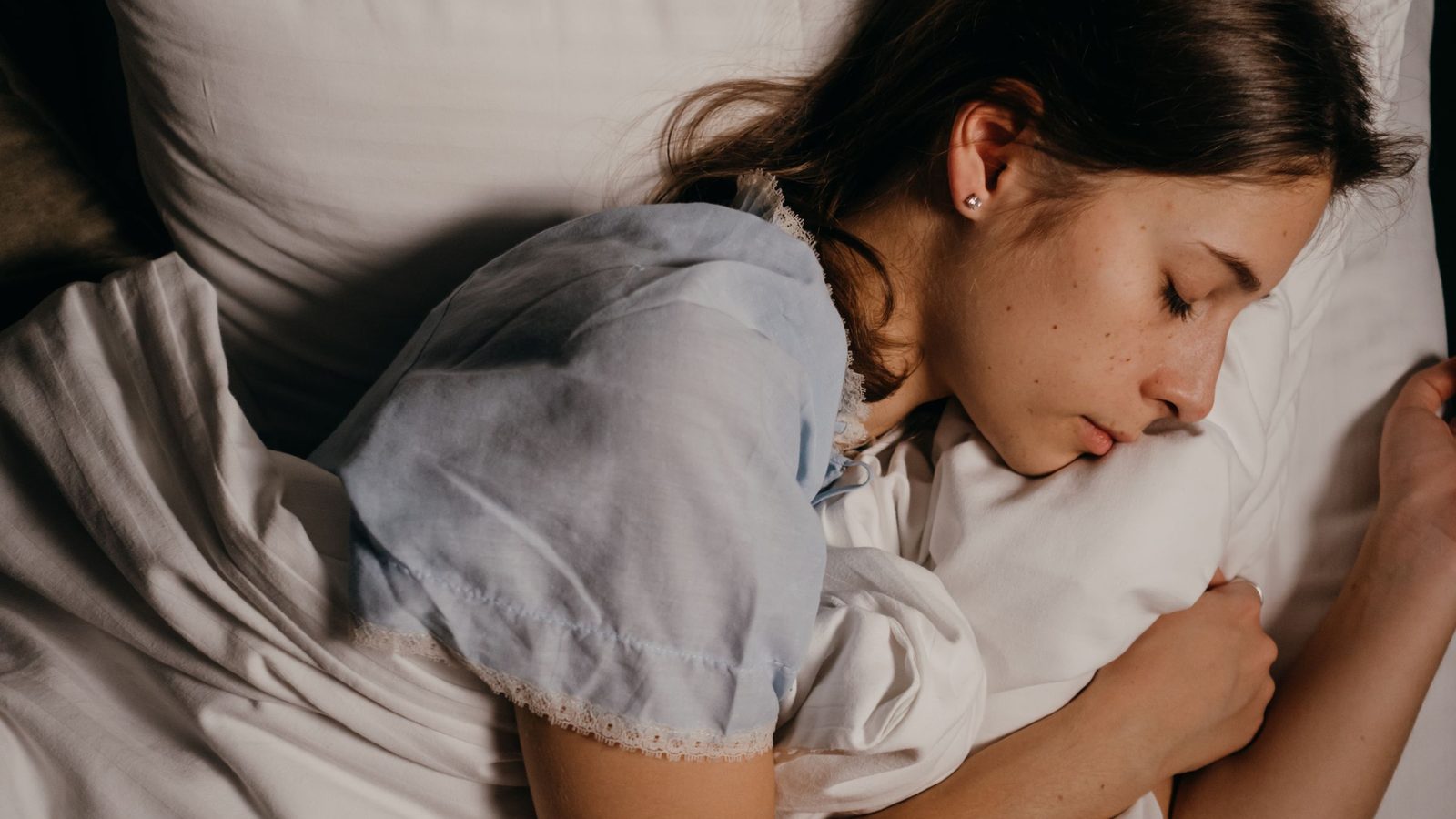 Woman sleeping peacefully on white bedding and pillow