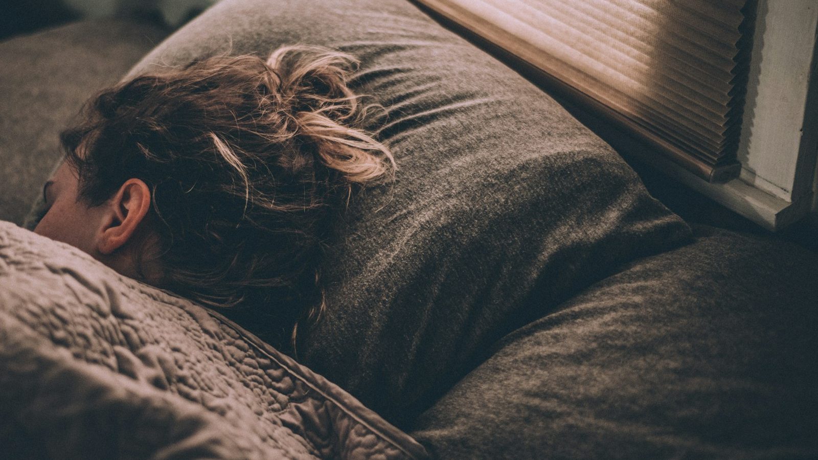 A student sleeping in bed during the morning hours, illustrating the struggle of waking up for early classes