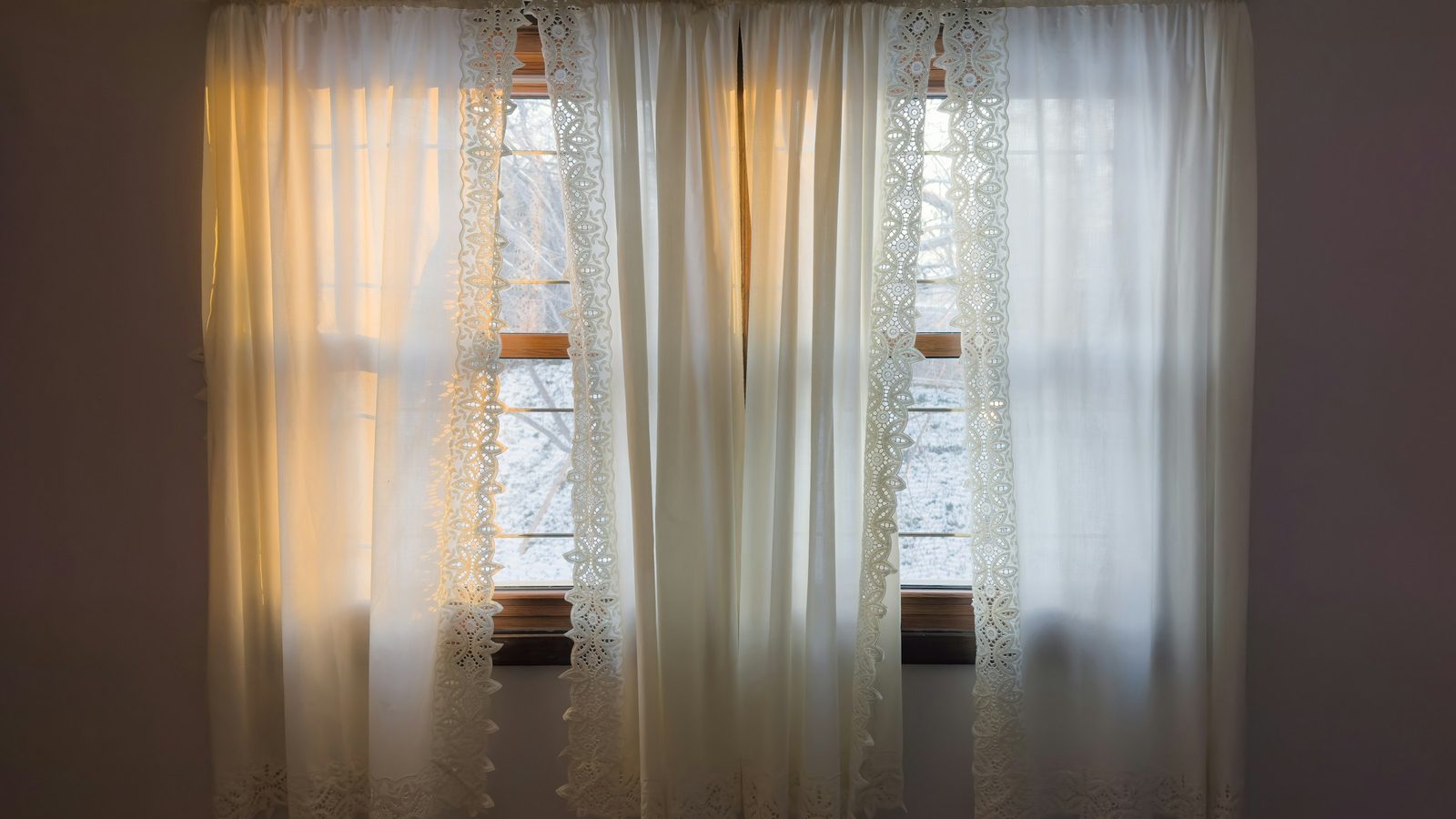 Bright morning sunlight filtering through white lace curtains and windows in a bedroom