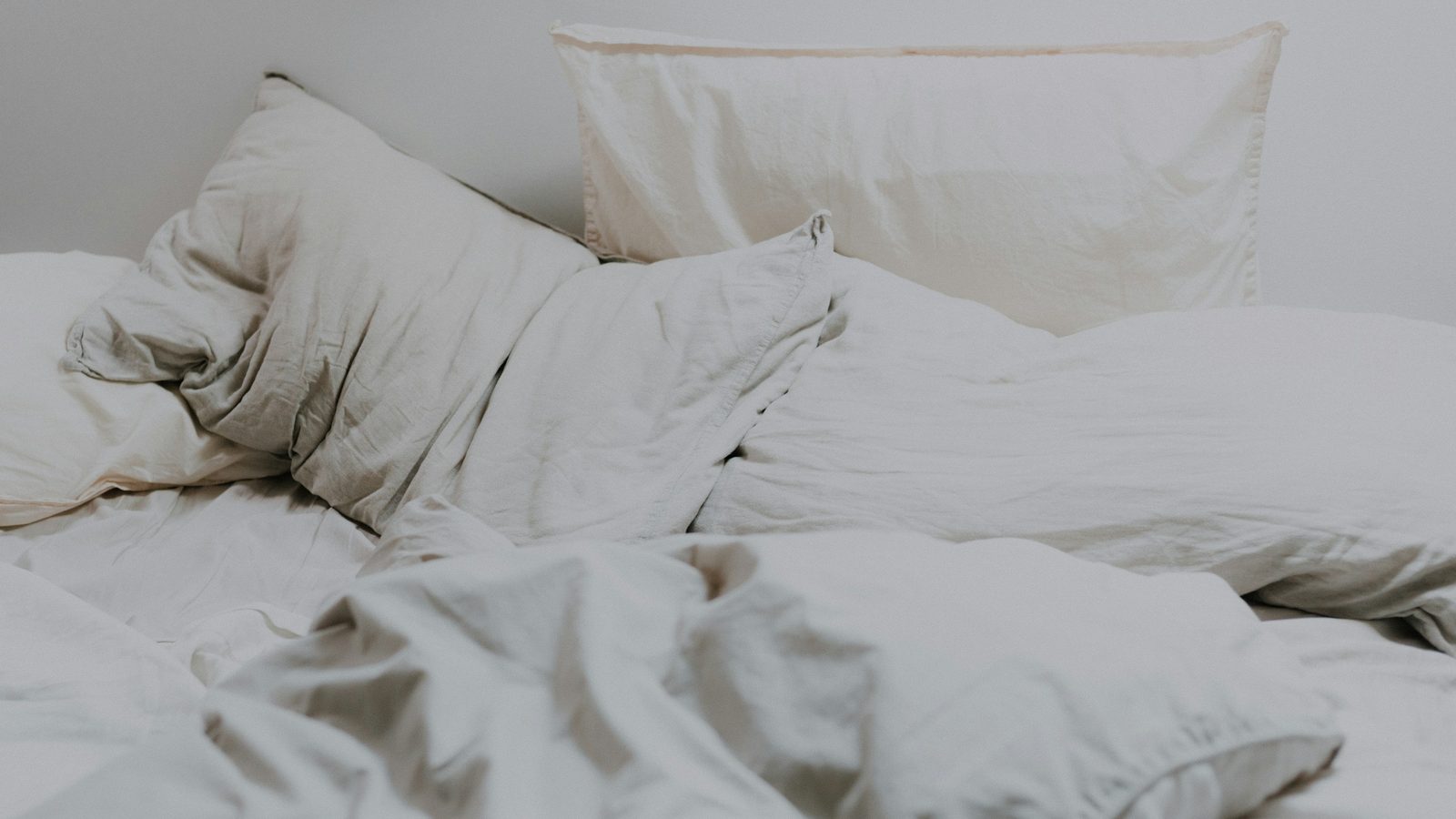 White pillows and rumpled bedding in soft morning light