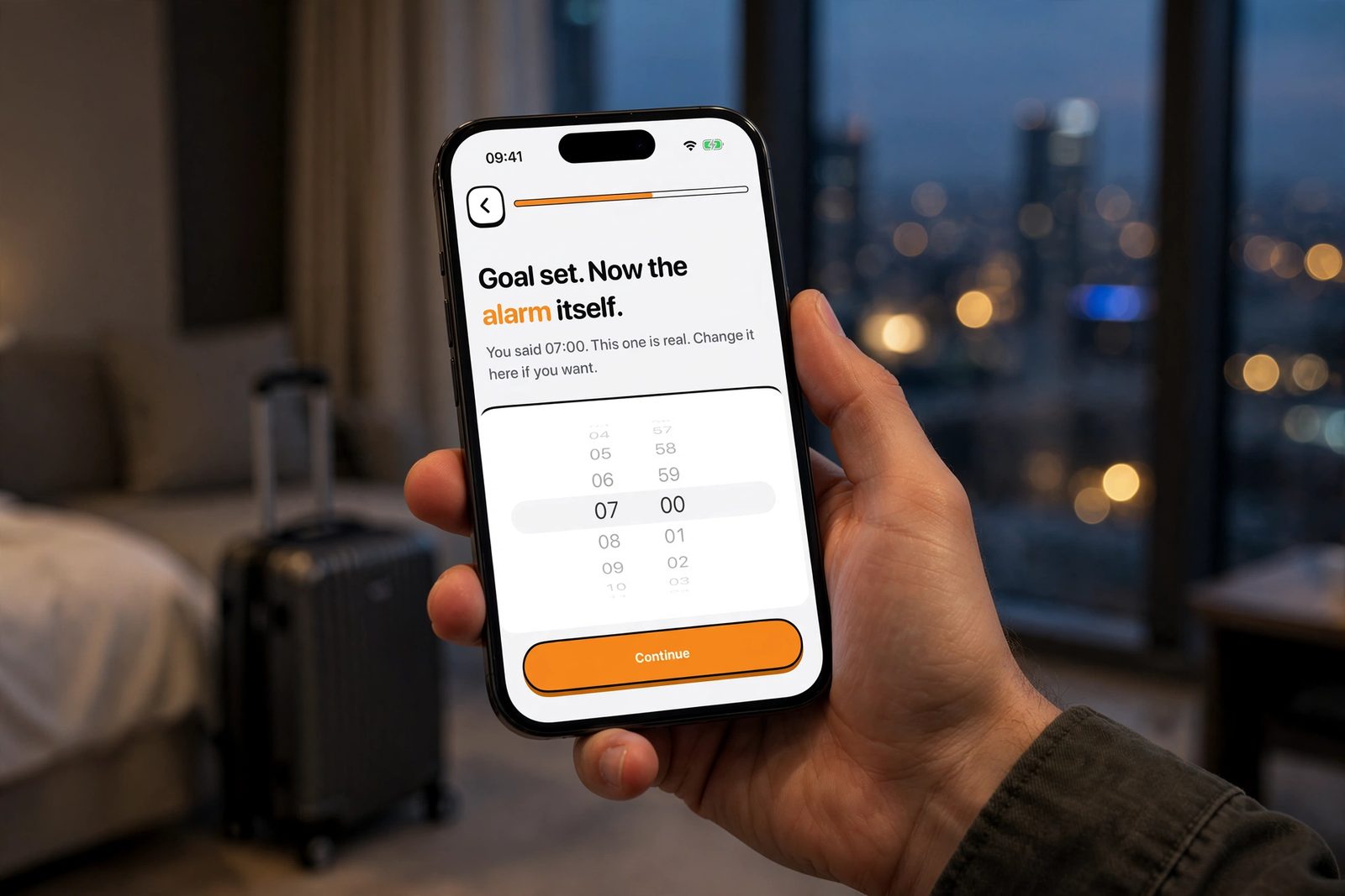 A hand holding an iPhone in a hotel room at dusk, showing NoNap's alarm time picker, used to set a wake up time ahead of a trip