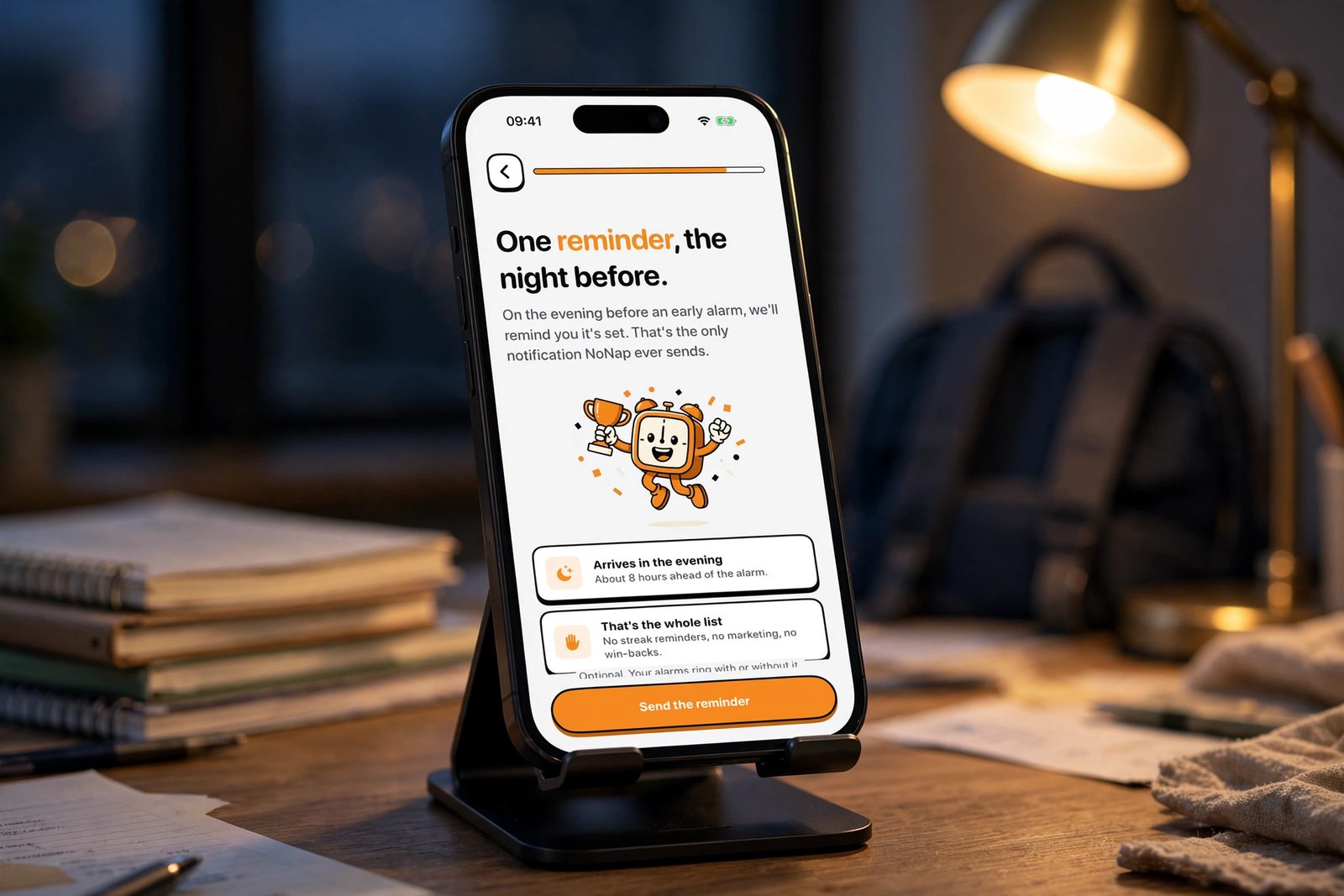 An iPhone on a desk next to school notebooks in the evening, showing NoNap's night-before reminder screen, sent the evening before an early alarm